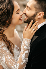 Beautiful wedding couple laugh and kiss on the background of stones.