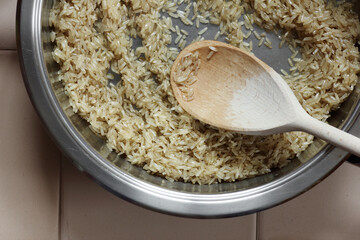 Rice frying and oiling in ghee  on steel pan closeup, process of cooking asian indian basmati ghee rice dish with