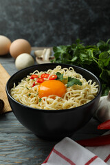 Bowl of cooked noodles and ingredients on wooden background