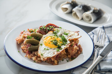 Norddeutscher Hamburger Labskaus mit Rindfleisch Corned Beef, Rote Beete, Kartoffeln, Saure Gurken, Spiegelei und Rollmops auf Emaille Teller