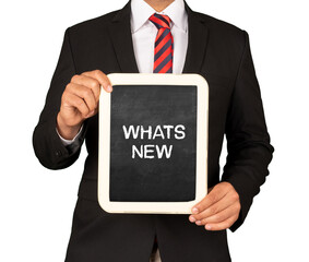 A Businessman holding slate mini blackboard with message What's New.