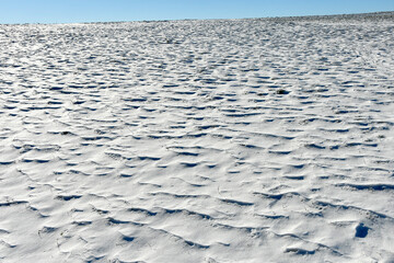 snow on a meadow with snowdrift and a blue sky