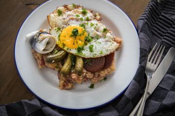 Norddeutscher Hamburger Labskaus mit Rindfleisch Corned Beef, Rote Beete, Kartoffeln, Saure Gurken, Spiegelei und Rollmops auf Emaille Teller