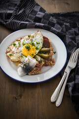 Norddeutscher Hamburger Labskaus mit Rindfleisch Corned Beef, Rote Beete, Kartoffeln, Saure Gurken, Spiegelei und Rollmops auf Emaille Teller
