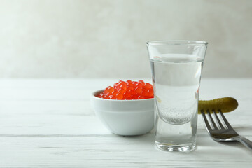 Shot of vodka, caviar and pickle on white wooden background