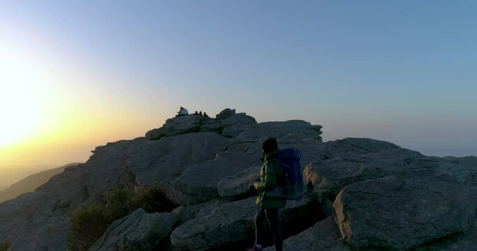 mujer aventurera y fot&oacute;grafa con mochila y mascarilla en cima de monta&ntilde;a al amanecer
