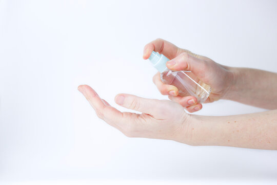 Female Hands Using Hand Sanitizer Spray Dispenser Againts White Background