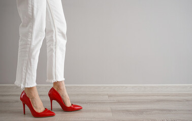 Legs of a young woman in jeans and shoes on a gray background, place for text.