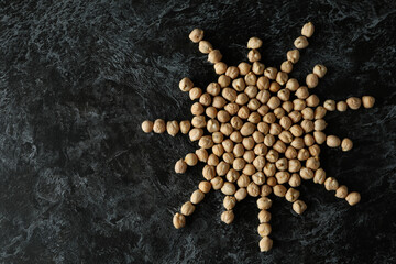 Sun made of chickpea on black textured background