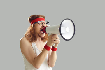 Funny noisy crazy nerdy young man in retro sportswear standing isolated on gray background, yelling...