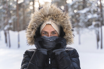 Young woman wearing down jacket with a hoodie during cold winter day