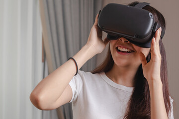 Pretty asian young woman touching,  wearing VR headset or visual reality goggles, glasses or gadget. Girl play videogame of simulator future,futuristic while wearable. Technology of modern concept.