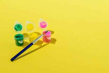 Set of acrylic paint with brush on yellow background