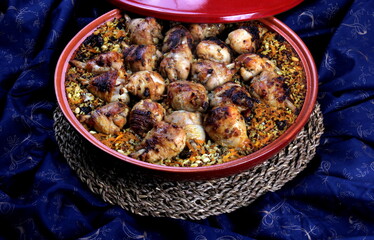 Traditional Tajine Berber Dish Made with Chicken Legs, couscous or rice, blue fabric background