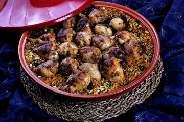 Traditional Tajine Berber Dish Made with Chicken Legs, couscous or rice, blue fabric background