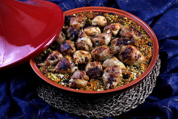 Traditional Tajine Berber Dish Made with Chicken Legs, couscous or rice, blue fabric background