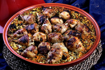 Traditional Tajine Berber Dish Made with Chicken Legs, couscous or rice, blue fabric background