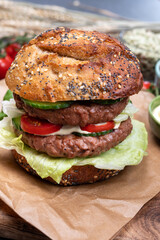 Tasty vegetarian vegan lunch with double decker hamburger made from plant based soya beans burger, organic bun with seeds and fresh vegetables