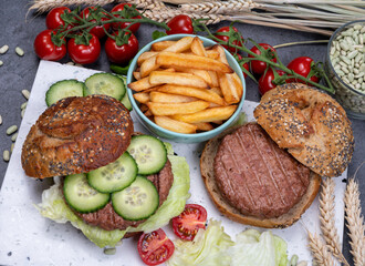Tasty vegetarian vegan lunch with hamburger made from plant based soya beans burger, organic bun with seeds and fresh vegetables and french fried potatoes