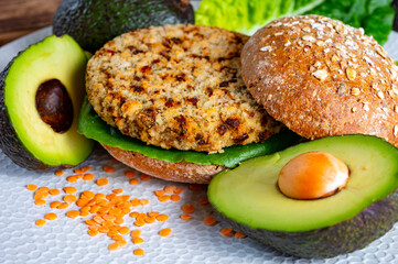 Tasty vegetarian healthy food, homemade burgers made from orange lentils legumes with green lettuce and fresh ripe avocado