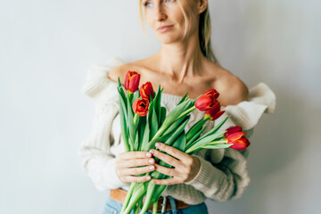 Cute beautiful blonde holds a bouquet of red tulips.