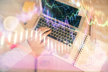 Double exposure of man's hands typing over computer keyboard and forex graph hologram drawing. Top view. Financial markets concept.