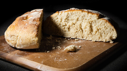 Fresh bread cut in half on wooden board