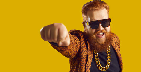 Shouting young man with ginger beard and handlebar mustache in funky leopard print suit and gold...