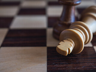 Wooden chess king defeated on a chessboard with copy space