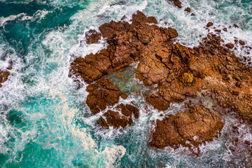 Aerial view of blue ocean surrounding  etched rocks and boulders