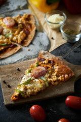Homemade Meat and Cheese thin crust Pizza on wood table with ingredients.