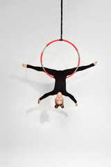 Little acrobat girl in black sportwear doing twine on an aerial hoop © Rychko Yevhen