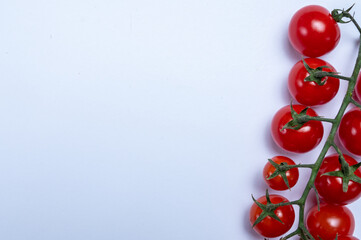 Vine of fresh ripe sweet cherry tomatoes ready to eat on white background