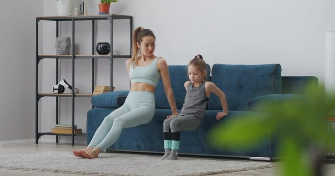 family training at morning, mother and daughter are doing physical exercises, push ups from couch