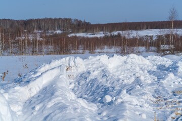 Piles of snow after the work of a tractor to clear rural roads in winter the consequences of heavy snowfall - 416492904