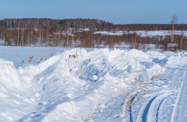 Piles of snow after the work of a tractor to clear rural roads in winter the consequences of heavy snowfall - 416492905