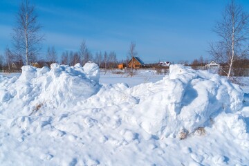 Piles of snow after the work of a tractor to clear rural roads in winter the consequences of heavy snowfall