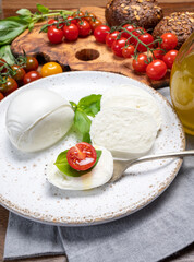Cheese collection, eating. of white soft Italian cheese mozzarella, served with red cherry tomatoes, fresh basil leaves