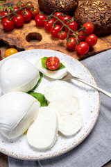 Cheese collection, eating. of white soft Italian cheese mozzarella, served with red cherry tomatoes, fresh basil leaves