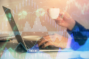 Double exposure of businesswoman hands typing on computer and forex graph hologram drawing....