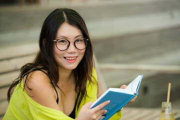 Asian woman in nerd style reading book - lifestyle portrait of young beautiful and happy Korean...
