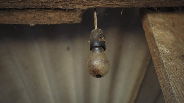 Dirty light bulb. An old lamp hangs from the ceiling. Abandoned house. The incandescent lamp with a tungsten filament on the wire.