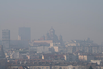 Smog lies over the skyline of Historical architecture of Belgrade city. Poor visibility, smog, caused by air pollution. Rooftop view. Emissions of plants and factories. Belgrade, Serbia 25.02.2021
