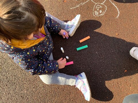 Ni&ntilde;a dibujando en el suelo con tizas de colores