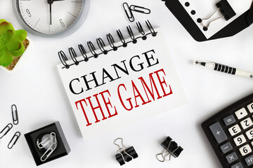 change the game. text on white notepad paper on light background near calculator, plant, table clock. - obrazy, fototapety, plakaty