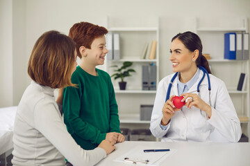 Happy woman and child listening to family doctor's advice. Smiling therapeutist or paediatrician telling mother and little son about importance of healthy lifestyle for maintaining good heart health