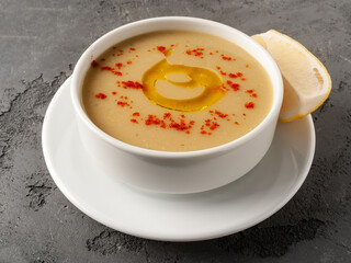 Lentil cream soup in white plate on gray concrete background