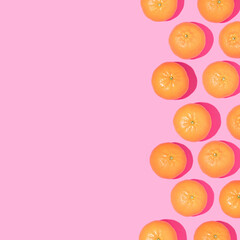 Creative pattern made with tangerines on bright pink background. Minimal flat lay. Spring or summer aesthetic concept. Fun idea with citrus fruits and copy space.