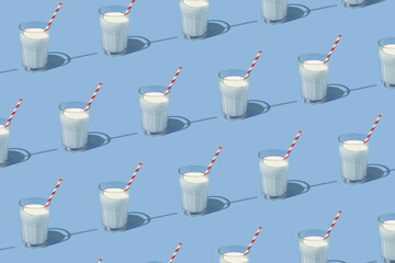 Creative pattern made with glass of milk and red and white paper straw on pastel blue background....