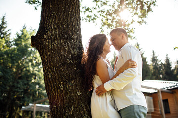 Fototapeta premium loving young couple having fun outdoors on summer sunny day. Man and woman are hugging near tree in park. valentines day
